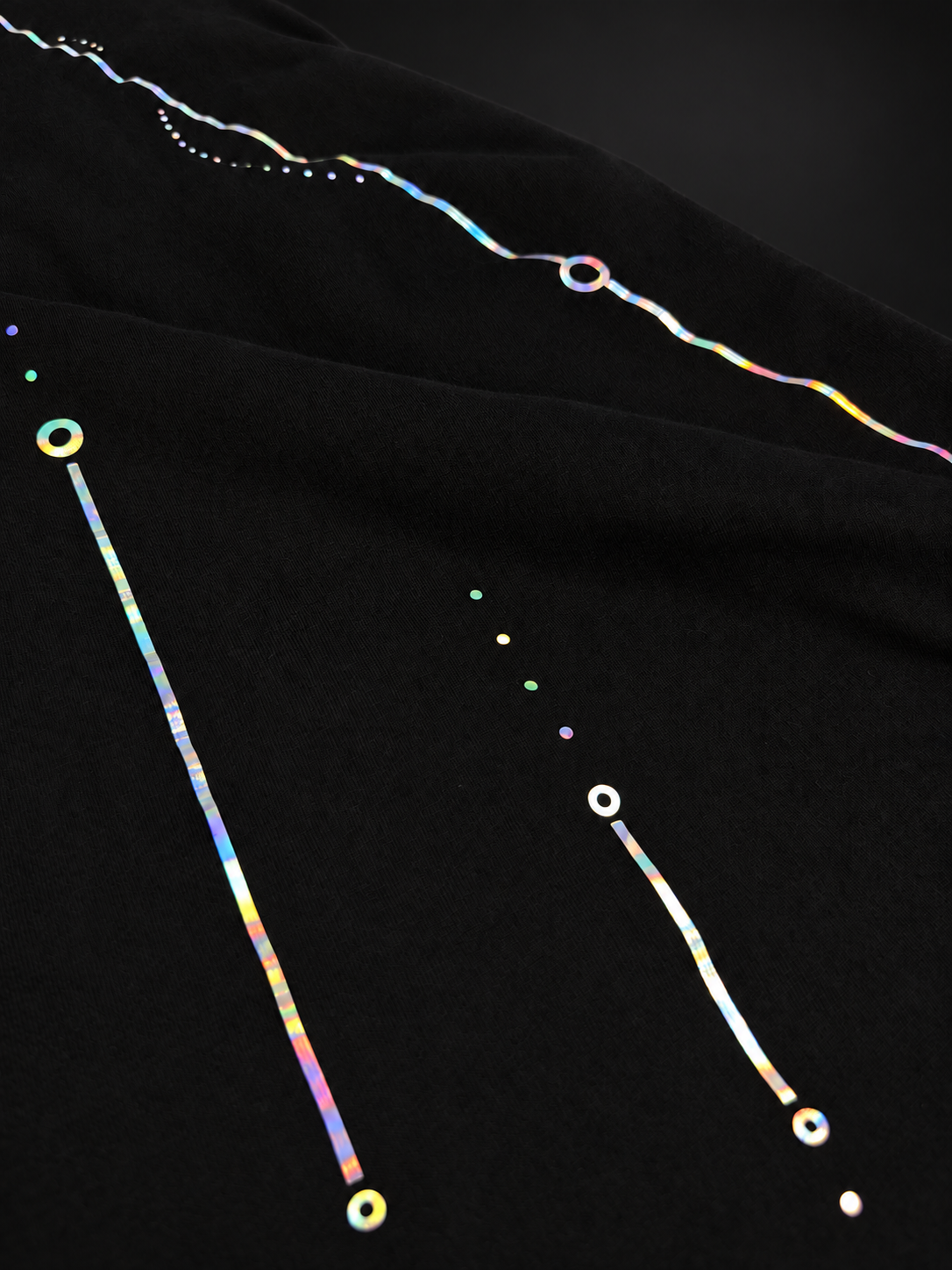 Close-up of the fine iridescent lines and circular details on the back of the ELAISSAOUI WLAD AISSA T-shirt.